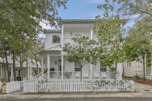 A two-story white house with a porch and a white picket fence.