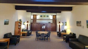 A lobby with a central table and chairs, a reception desk, and a wooden bookshelf. - 2-Bed. 2-Bath. Downtown Winter Park Condo CB2 (Winter Park)