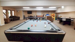 A pool table with balls, a sofa, a television, and a play area with toys. - 2-Bed. 2-Bath. Downtown Winter Park Condo CB2 (Winter Park)