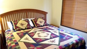 A bed with a colorful quilt, a wooden headboard, and a window with blinds. - 2-Bed. 2-Bath. Downtown Winter Park Condo CB2 (Winter Park)