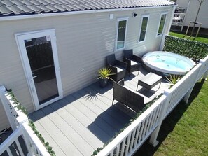 Terraza con mobiliario exterior, una bañera de hidromasaje y un ventanal corredero.