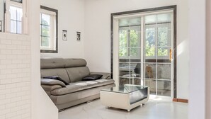 Una sala de estar moderna con un sofá de cuero, una mesa de centro de vidrio y un ventanal corredero que da a un balcón.