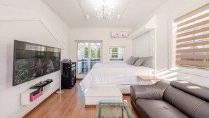 Un dormitorio con cama, televisor, sofá y balcón.
