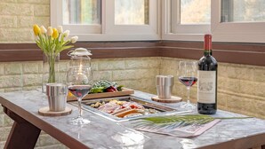 Una mesa de mármol con una botella de vino, copas, una vela, una bandeja de comida y un jarrón de tulipanes.