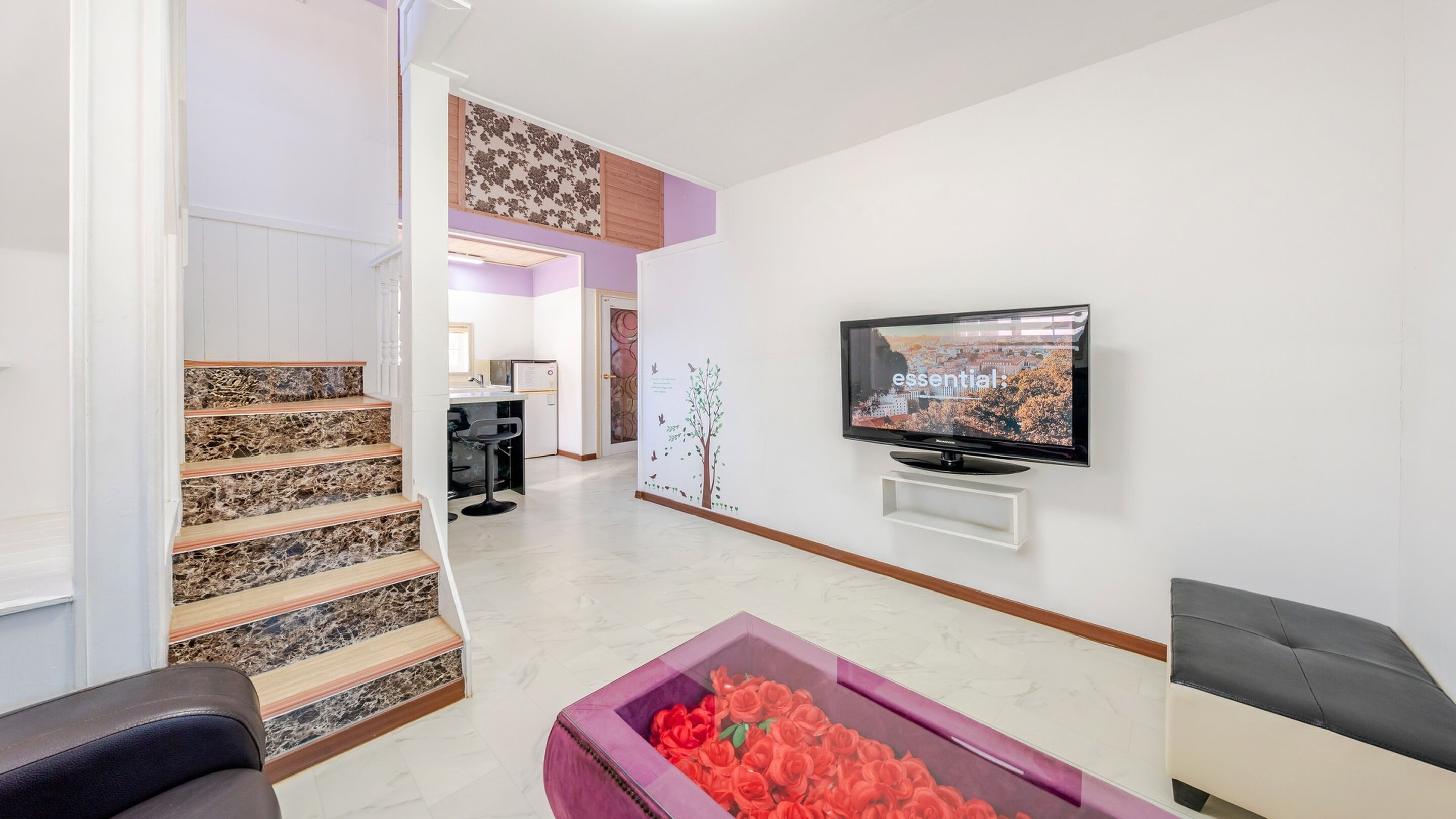 Ein modernes Wohnzimmer mit Treppe, Flachbildfernseher und einer dekorativen Blumenkiste.