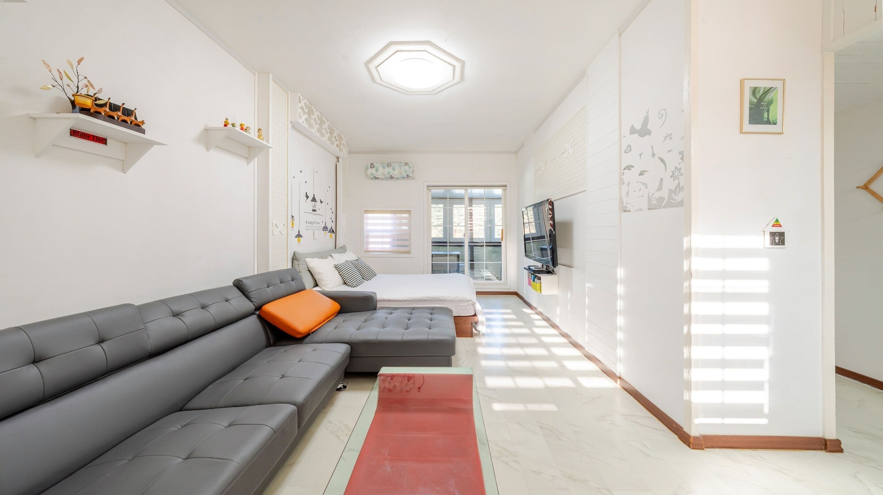 Een moderne woonkamer met een grijze modulaire bank, een rood tapijt en een balkon met uitzicht.