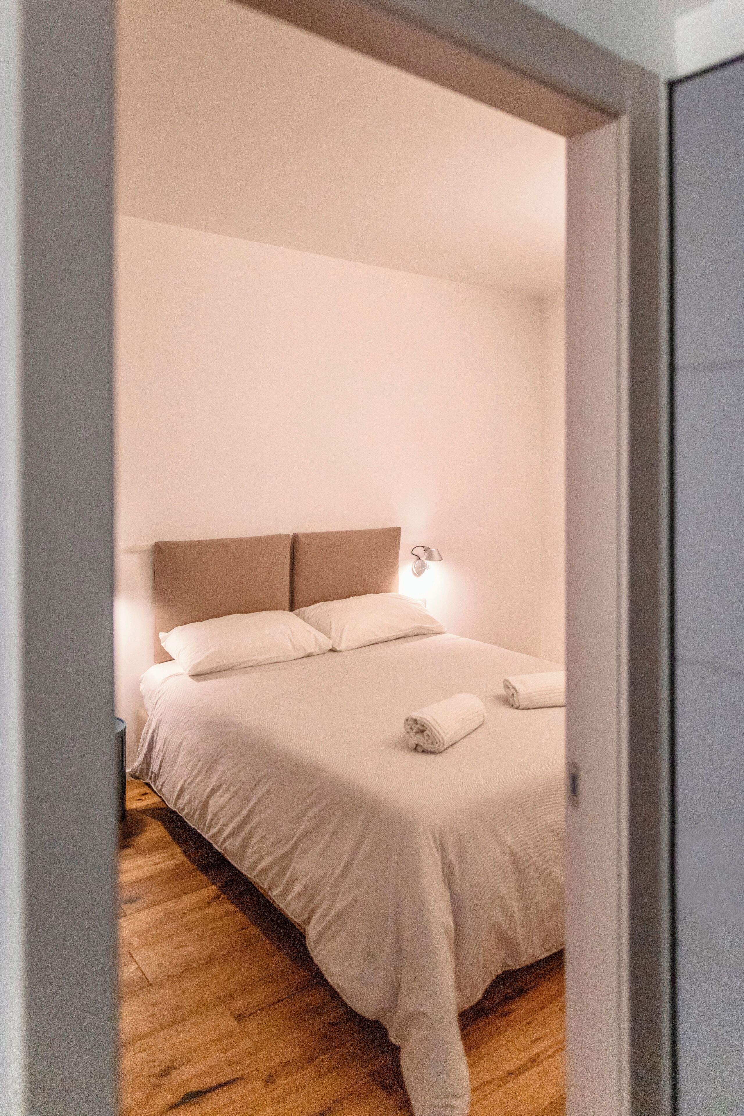 A bedroom with a bed, a nightstand, and a wall-mounted light.