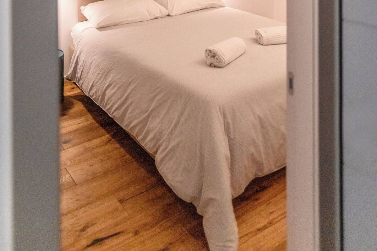 A bedroom with a bed, a nightstand, and a wall-mounted light.