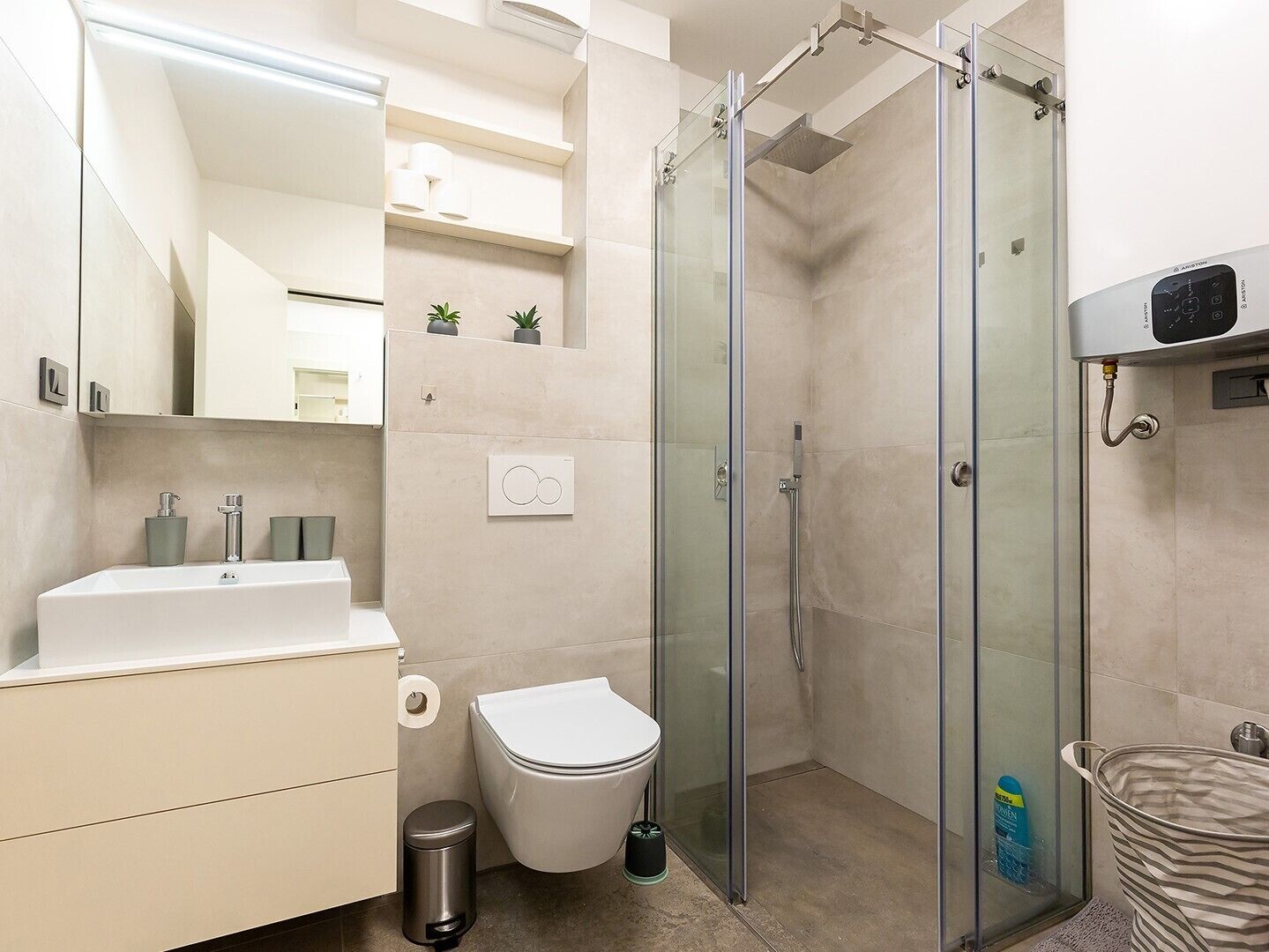 A modern bathroom with a glass-enclosed shower, a white sink, and a toilet.