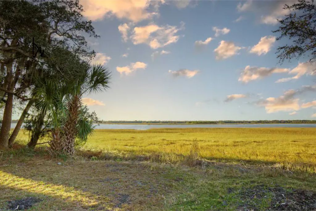 Een natuurlandschap met water, bomen en open velden.