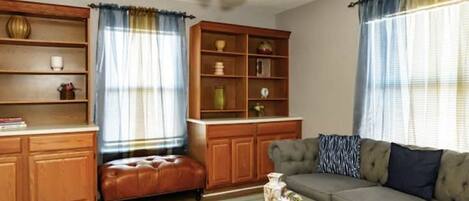A living room with a sofa, a coffee table, a bookshelf, and a ceiling fan.