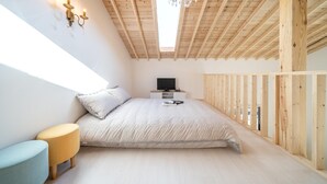 A bedroom with a bed, a TV, and a small table. - Gangneung Ggabinejip Hanok Pension (Gangneung)