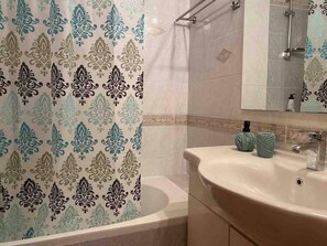 A bathroom with a bathtub, a sink, and a mirror. - Well Designed 2 Bdr Apartment (Ioannina)