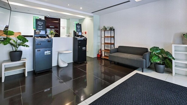 A modern reception area with a check-in counter, a seating area with a sofa, and a reception desk. - Check inn Express Taipei Yongkang (Taipei)