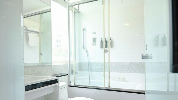 A modern bathroom with a glass shower enclosure, a white toilet, and a vanity with a mirror. - Check inn Express Taipei Yongkang (Taipei)