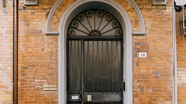 Un edificio de ladrillo con una amplia y ornamentada puerta de metal.