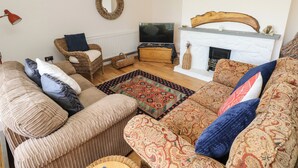 A cozy living room with a fireplace, a television, and comfortable seating. - Glynderi (Cardigan)