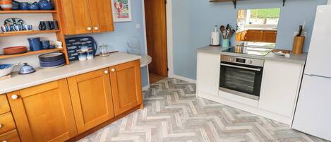 A kitchen with wooden cabinets, a herringbone-patterned floor, and a built-in oven.
