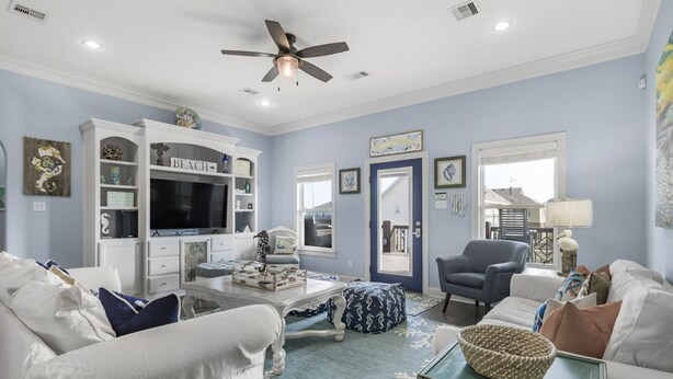 A living room with a white sofa, a blue armchair, a coffee table, and a bookshelf labeled "BEACH".
