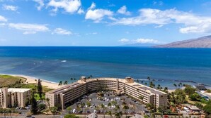 A hotel with a curved building, a parking lot, and a beach view. - Menehune Shores, #623 2 Bedroom Condo by RedAwning (Kihei)