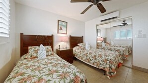 A hotel room with two beds, a ceiling fan, a mirror, and a window with blinds. - Menehune Shores, #623 2 Bedroom Condo by RedAwning (Kihei)