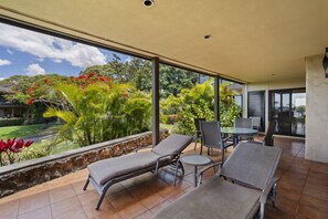 A balcony with two lounge chairs, a small table, and a view of a garden with various plants and trees. - Wailea Elua, #2003 1 Bedroom Condo by RedAwning (Kihei)