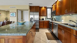A modern kitchen with wooden cabinets, stainless steel appliances, and a granite countertop. - Wailea Elua, #2003 1 Bedroom Condo by RedAwning (Kihei)