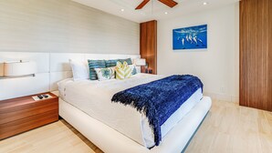Un dormitorio moderno con una cama grande, un ventilador de techo y una obra de arte colgada en la pared.