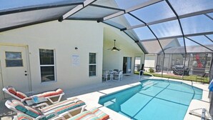 A swimming pool area with lounge chairs and a covered patio. - Palm Villa 4 Bedroom Home by RedAwning (Haines City)