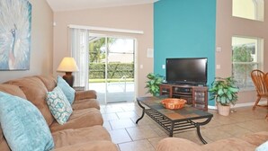 A living room with a sofa, a TV, and a coffee table. - Palm Villa 4 Bedroom Home by RedAwning (Haines City)