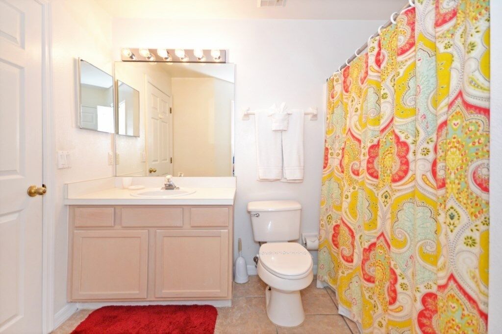 Ein Badezimmer mit Waschbecken, Spiegel und Toilette. Zwei Handtücher hängen an der Wand.