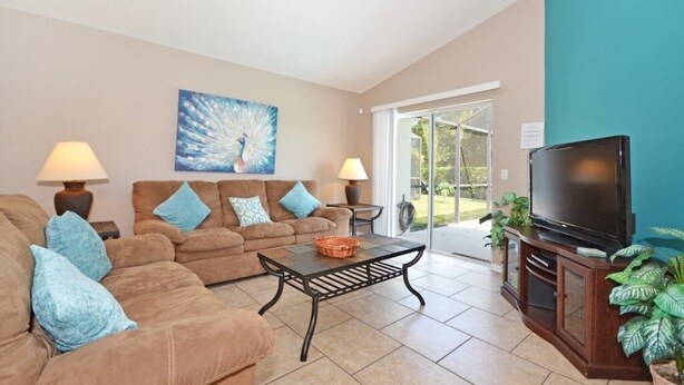 A living room with a sofa set, a coffee table, a TV, and a painting on the wall. - Palm Villa 4 Bedroom Home by RedAwning (Haines City)