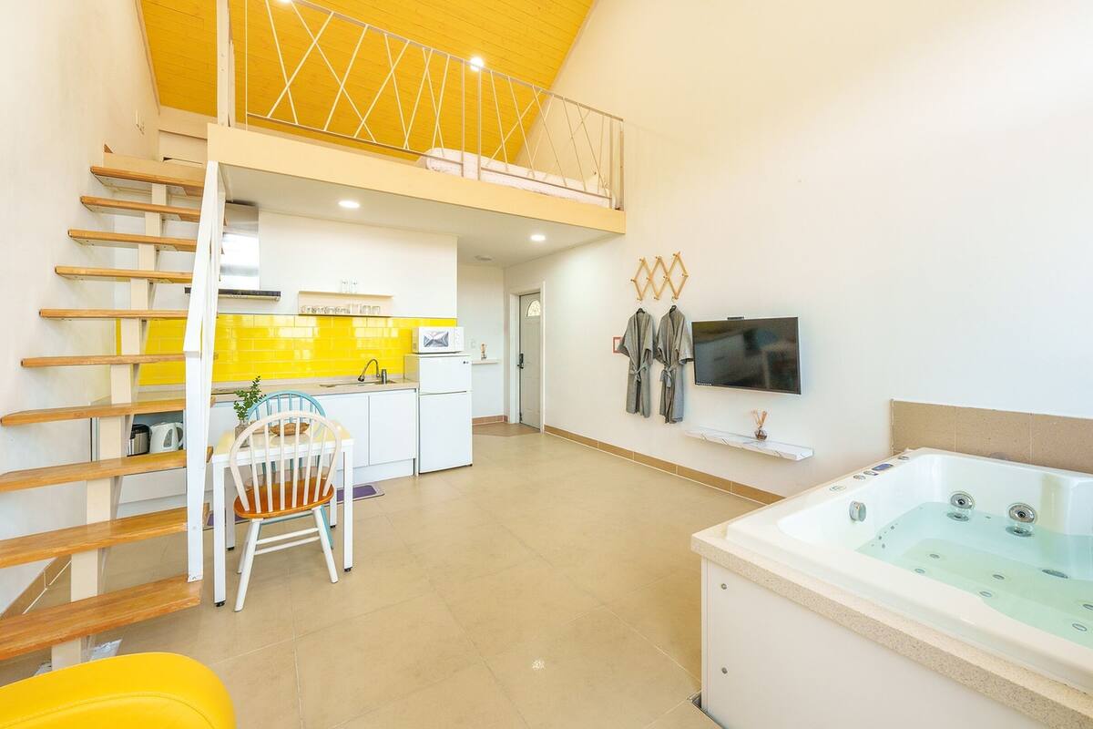 A modern apartment with a kitchen, dining area, and a living room with a large bathtub.