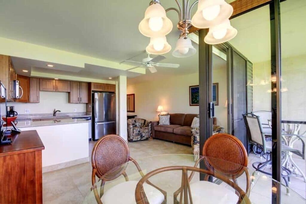 Una cocina moderna con refrigerador, estufa y comedor con sillas y mesa.