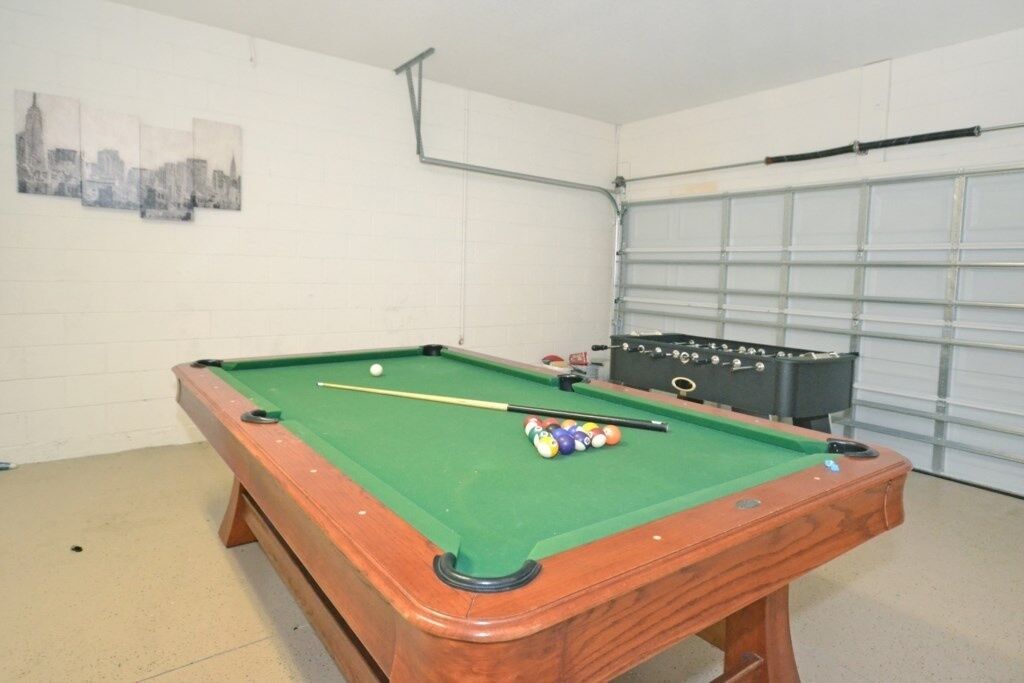 Een pooltafel met ballen en keus, een tafelvoetbaltafel en een stadsgezicht als kunstwerk aan de muur.