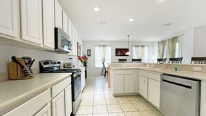 Una cocina moderna con armarios blancos, microondas, estufa y lavavajillas.