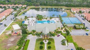 Vue aérienne d’un complexe hôtelier doté d’une piscine centrale, de courts de tennis et d’un parking.