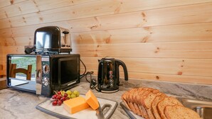 A kitchen with a microwave, toaster, kettle, cheese, grapes, and sliced bread on a marble countertop. - Cherry (Ulverston)