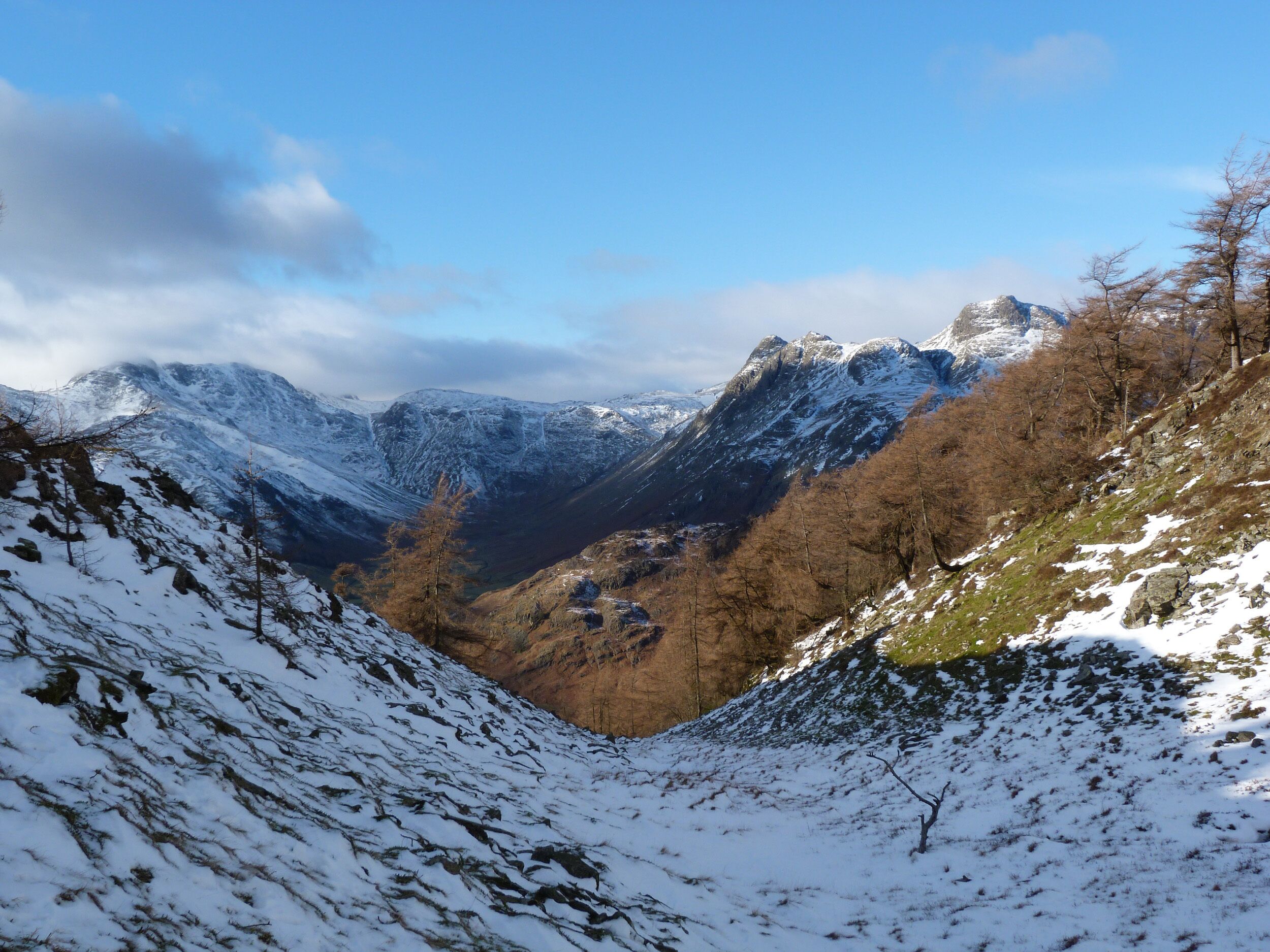 A mountainous landscape with snow-covered slopes and a valley.