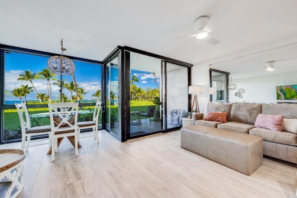 A spacious living area with a large sliding glass door leading to a balcony, a sofa, and a dining table with chairs.