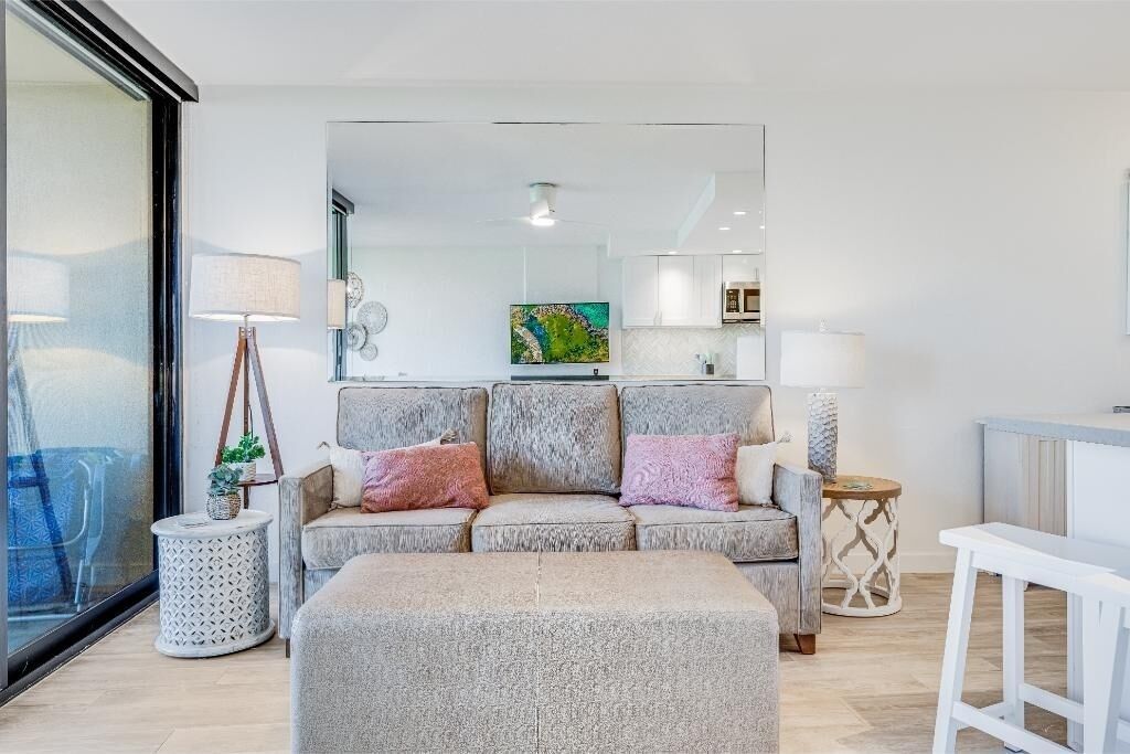 A modern living room with a sofa, ottoman, and a small side table.