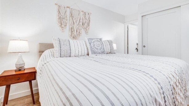 Un dormitorio con una cama, una mesita de noche, un adorno en la pared y una puerta.