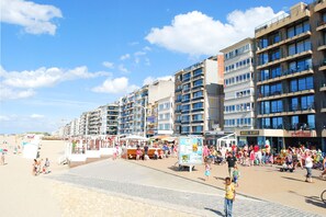 Un paseo marítimo frente a la playa, con edificios de varios pisos, un malecón y una multitud de gente.