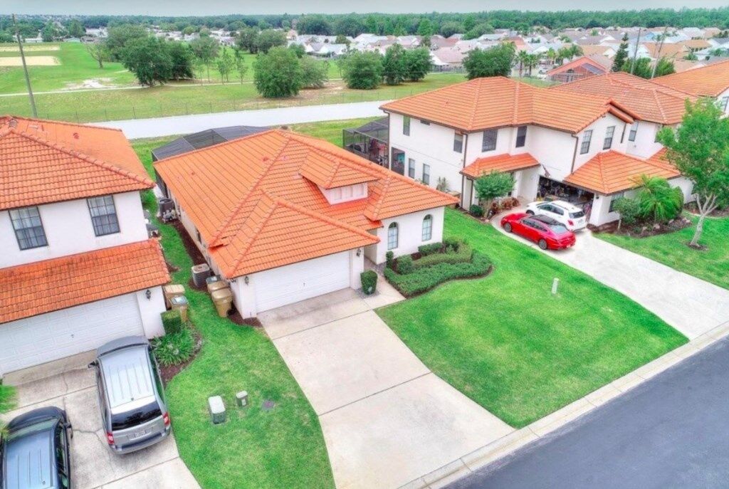 A residential area with houses featuring red-tiled roofs, a well-maintained lawn, and a clear view of the neighborhood.