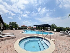 Un espace piscine avec des chaises longues et un coin salon abrité.