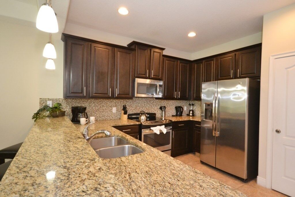 A modern kitchen with granite countertops, stainless steel appliances, and dark wood cabinets.