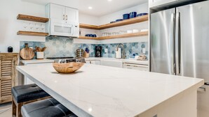 A modern kitchen with a central island, stainless steel appliances, and wooden accents. - Kihei Surfside, #113 1 Bedroom Condo by RedAwning (Kihei)