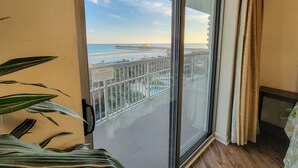 A balcony with a view of a beach and pier.