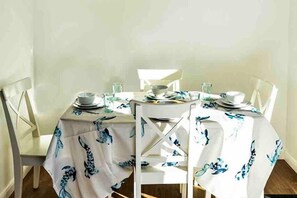 A dining table set with plates, bowls, and glasses, covered with a white tablecloth featuring a blue pattern. - Standrews- Sleeps4- Familyfriendly- Newlyrenovated (St. Andrews)