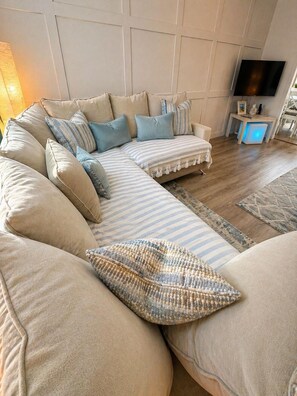 A modern living room with a sectional sofa, a flat-screen TV, and a small side table. - Standrews- Sleeps4- Familyfriendly- Newlyrenovated (St. Andrews)